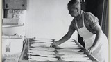 Mr L Feather in his bakery at Haworth making oatcake: placing the finished oatcake onto a wire tray. Associated with the series of photographs used to illustrate "Life and Tradition in West Yorkshire" (1976), cp.plates 98-102.