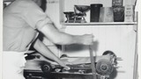 Mr L Feather in his bakery at Haworth making oatcake: pulling the lever which jerks the tram forward to throw the batter on to the bakestone. Associated with the series of photographs used to illustrate "Life and Tradition in West Yorkshire" (1976), cp.pl