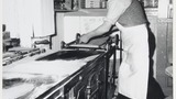 Mr L Feather in his bakery at Haworth making oatcake: transferring the batter on to the cloth of the tram. Associated with the series of photographs used to illustrate "Life and Tradition in West Yorkshire" (1976), cp.plates 98-102.